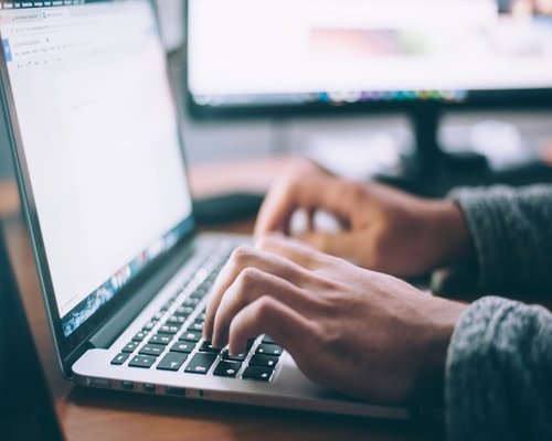 Person typing on a laptop working on editorial content