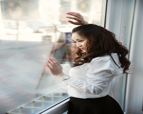 Person resting eyes by looking out the window of a city bus
