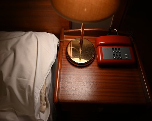 A bedside table with a book and a glass of water, phone placed face down